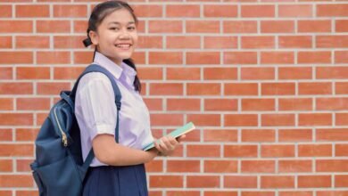 A female school children smiling in front of a brick wall