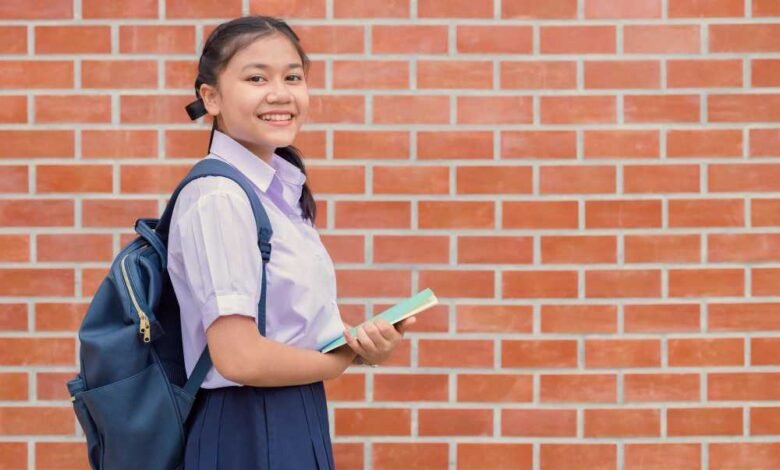 A female school children smiling in front of a brick wall